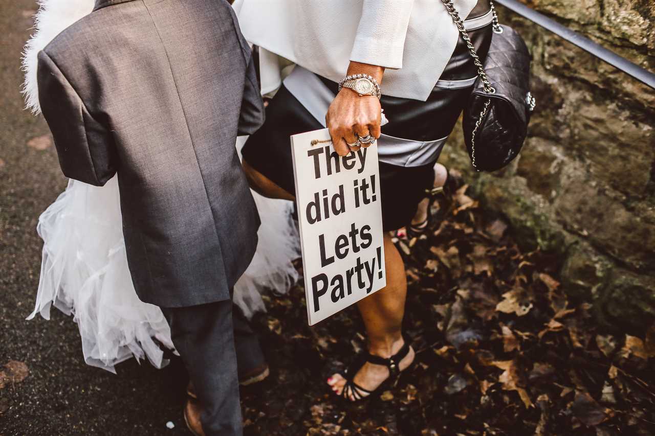 woman holding a fun sign after the wedding ceremony