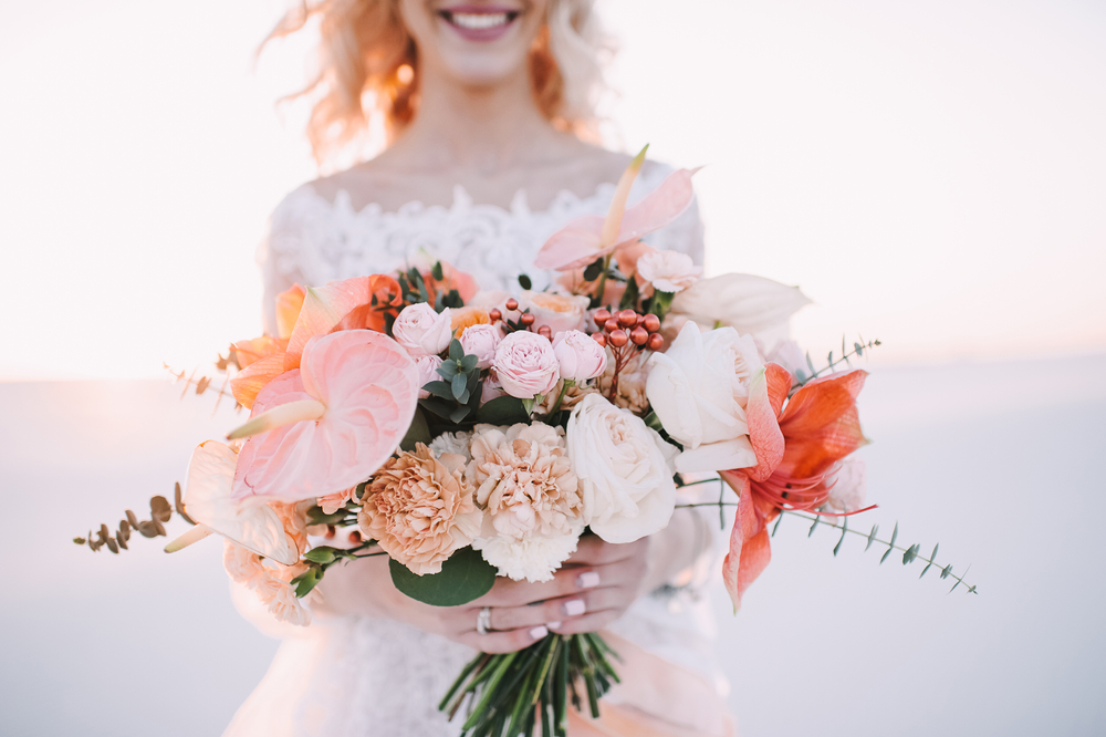 Close-up of a bride’s bouquet of amaryllis, anthurium, roses, carnations, eucalyptus in white-peach shades.