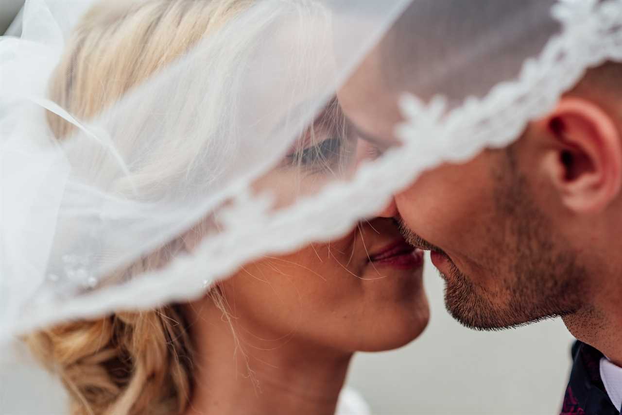bride and groom kissing under a wedding veil