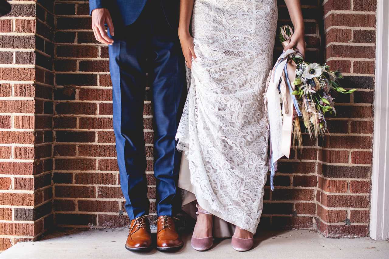 bride and groom against a brick wall